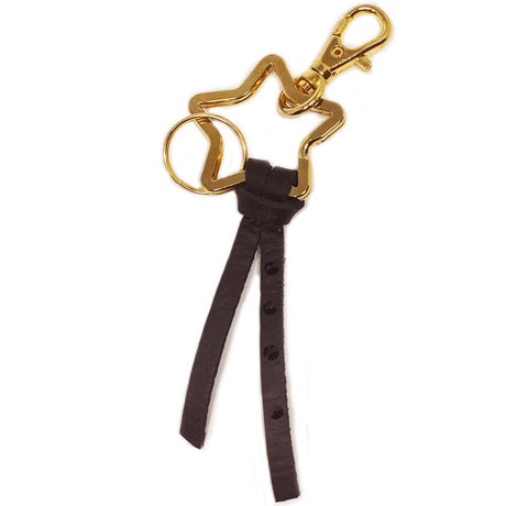A gold-colored metal keychain with a star-shaped charm and a black leather strap, with brass accents.