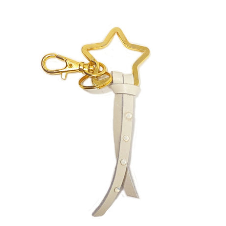 A gold-colored metal bag-charm with a white leather strap and Austrian crystals, designed in the shape of a star.